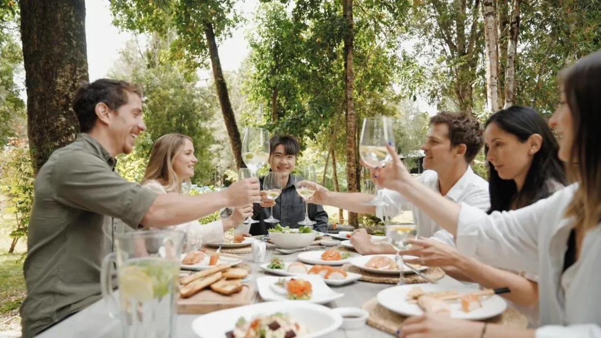 Grupo brindando en un almuerzo al aire libre entre árboles
