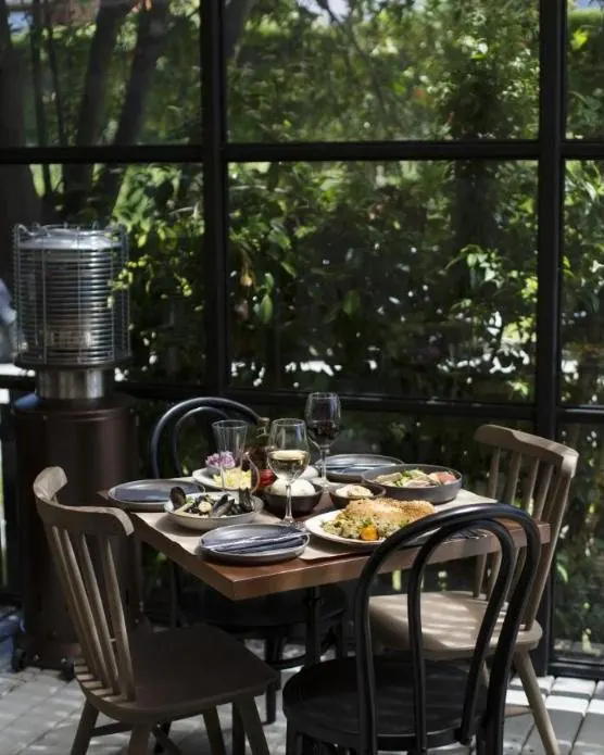 Terraza de restaurante entre árboles con mesas servidas